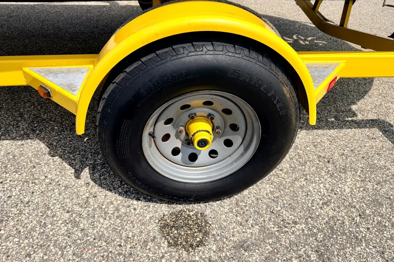 Slide: The Image of Yellow trailer wheel of 2008 Starcraft Aurora Star Step 190 IO on asphalt. - 84