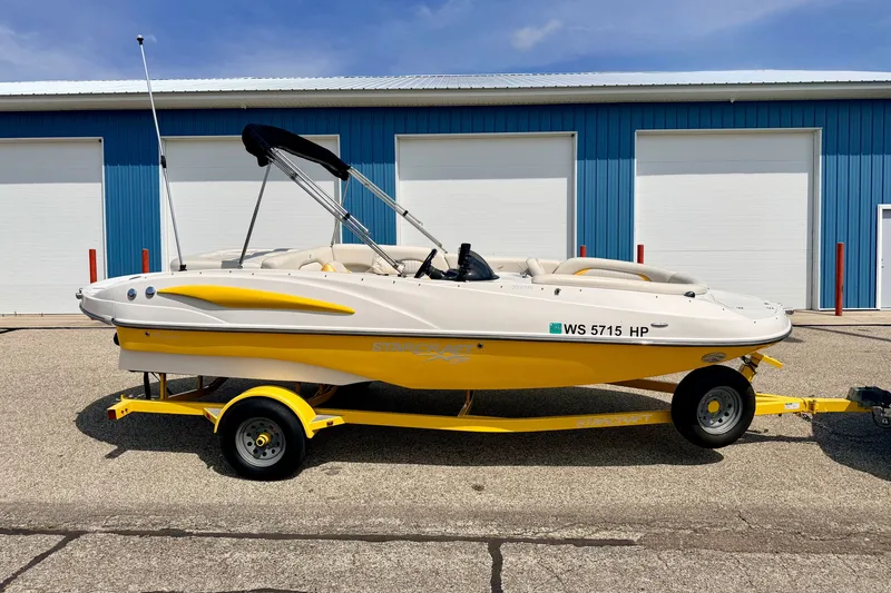 Slide: The Image of 2008 Starcraft Aurora Star Step 190 IO boat on trailer, parked near blue building. - 2
