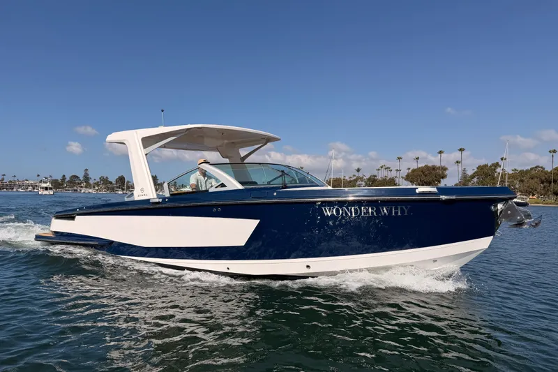 Slide: The Image of 2022 Aviara AV32 I/O boat cruising on water, blue and white design, clear sky background. - 2