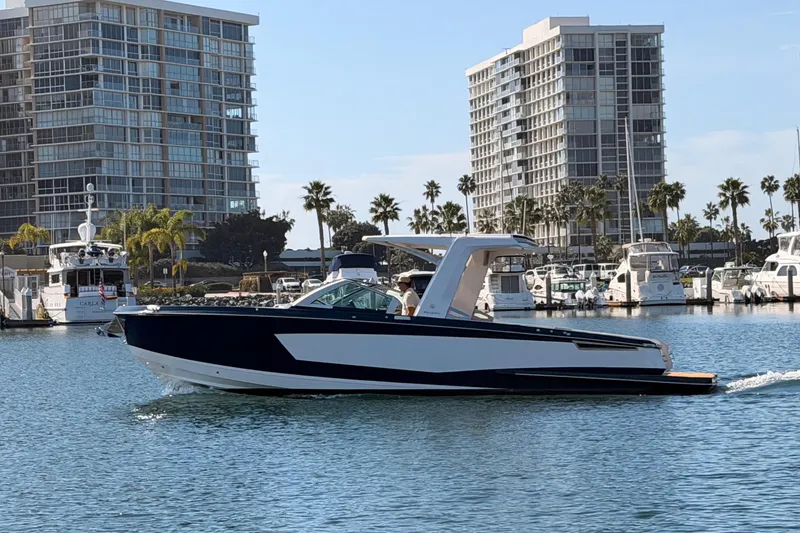 The Image of 2022 Aviara AV32 I/O boat cruising in a marina with modern buildings in the background. - 0
