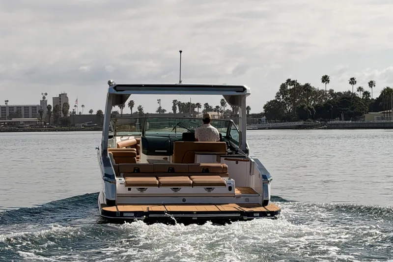 Slide: The Image of 2022 Aviara AV32 I/O boat cruising on calm waters near a cityscape. - 4