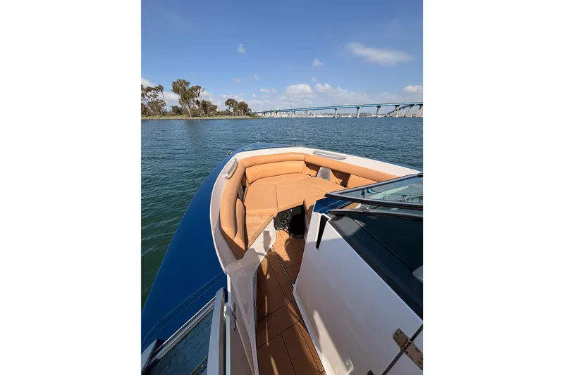 Slide: The Image of 2022 Aviara AV32 I/O boat on water, featuring tan seating and scenic bridge view. - 15
