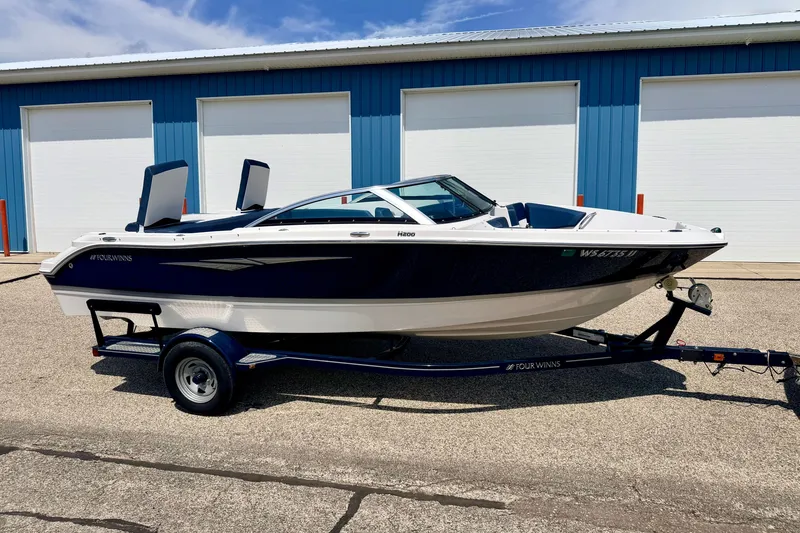 The Image of 2014 Four Winns H200 boat on trailer, parked outside blue storage units. - 0