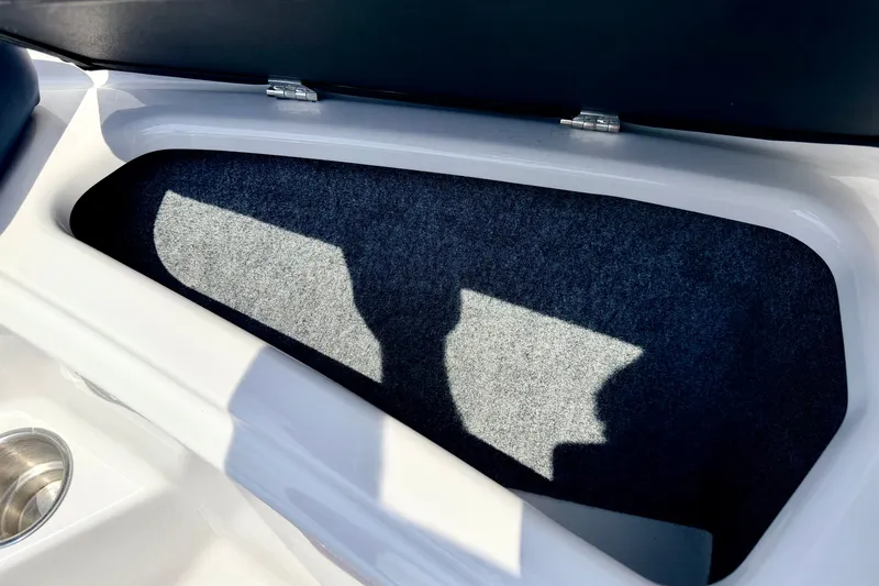 Slide: The Image of Storage compartment in 2014 Four Winns H200 boat, featuring carpeted interior and stainless steel cup holder. - 72