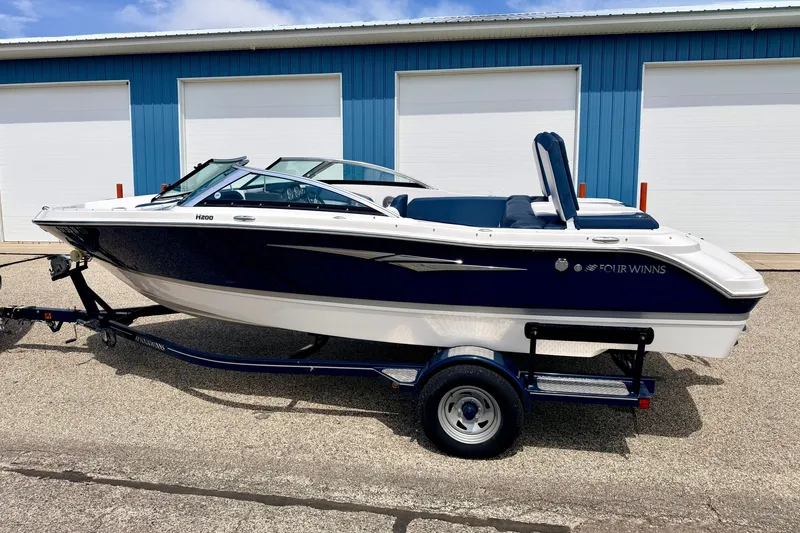 Slide: The Image of 2014 Four Winns H200 boat on trailer, parked near blue storage units. - 3
