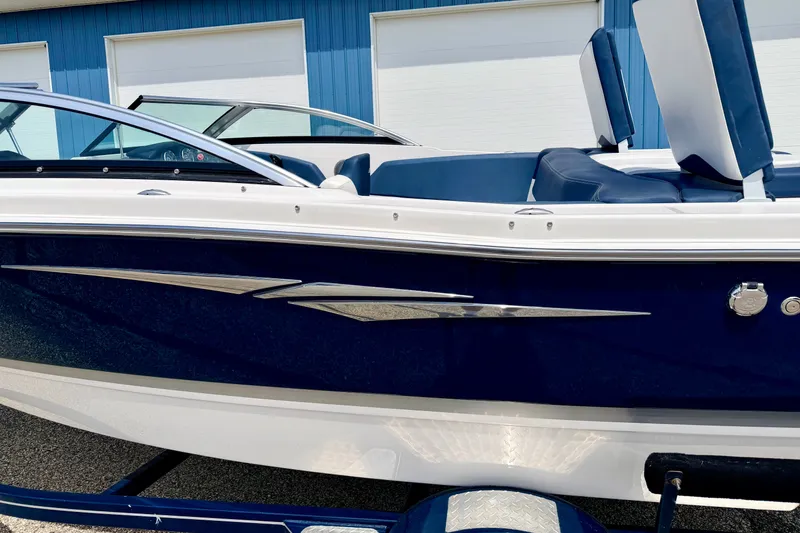 Slide: The Image of 2014 Four Winns H200 boat with sleek blue and white design, parked near a blue building. - 16