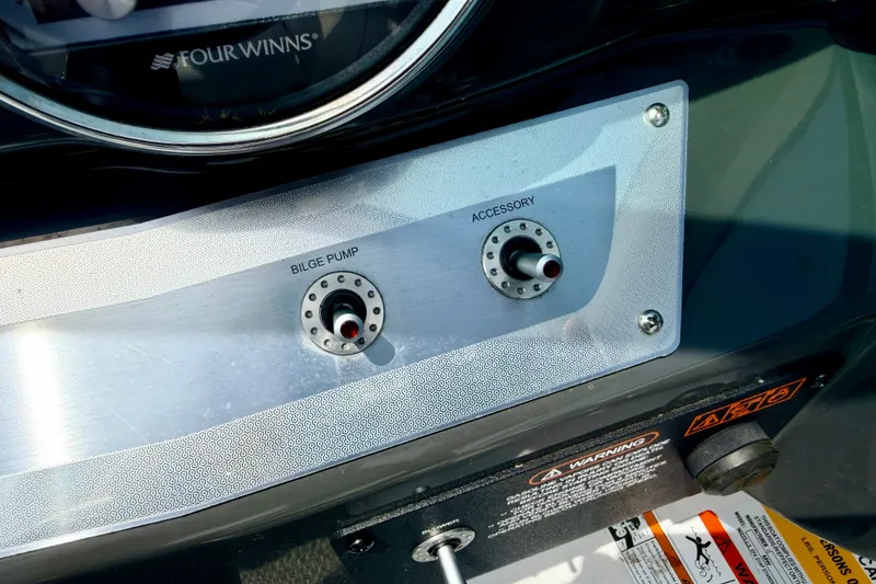 Slide: The Image of Control panel of a 2014 Four Winns H200 boat with bilge pump and accessory switches. - 56