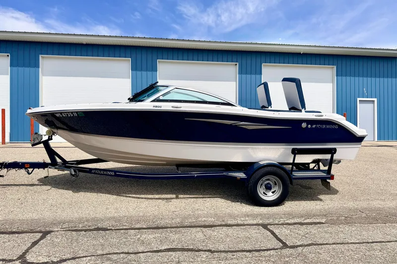 Slide: The Image of 2014 Four Winns H200 boat on trailer, parked in front of blue warehouse. - 5