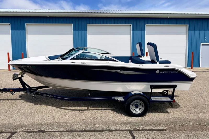 Slide: The Image of 2014 Four Winns H200 boat on trailer, parked in front of blue garage doors. - 1