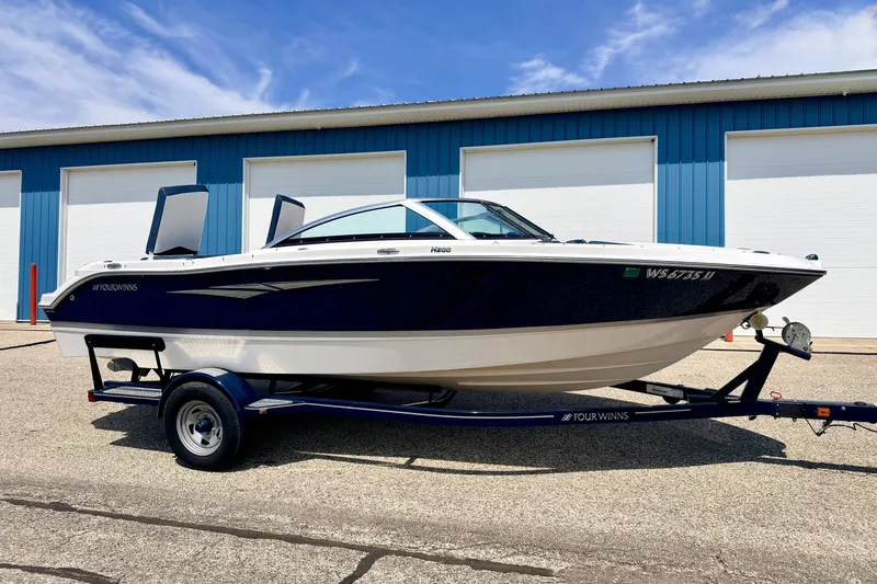 Slide: The Image of 2014 Four Winns H200 boat on trailer, parked outside blue storage units. - 4