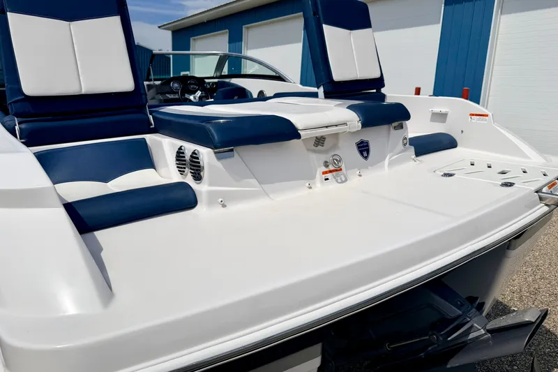 Slide: The Image of 2014 Four Winns H200 boat with blue and white seating, docked near a blue building. - 21