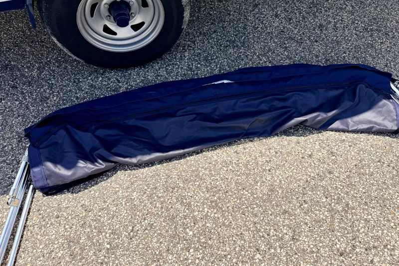 Slide: The Image of Folded navy blue boat cover on pavement near a trailer wheel, Four Winns H200 2014. - 81