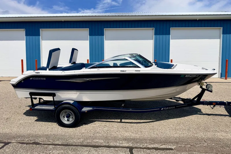 Slide: The Image of 2014 Four Winns H200 boat on trailer, parked outside blue building. - 2