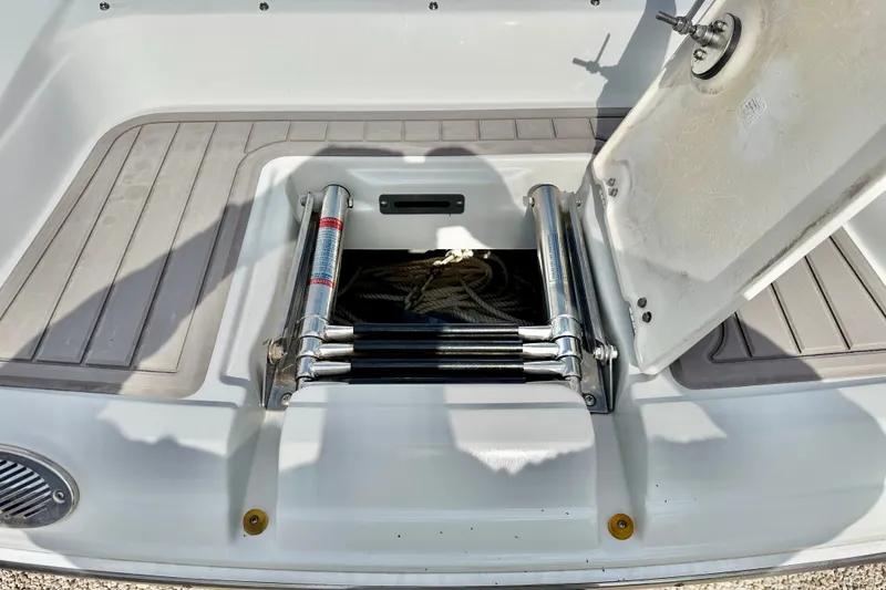 Slide: The Image of 2024 Crownline Eclipse E285 XS boat ladder compartment with open hatch and stored ropes. - 23