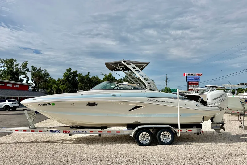 The Image of 2024 Crownline Eclipse E285 XS boat on trailer, parked outdoors under cloudy sky. - 0