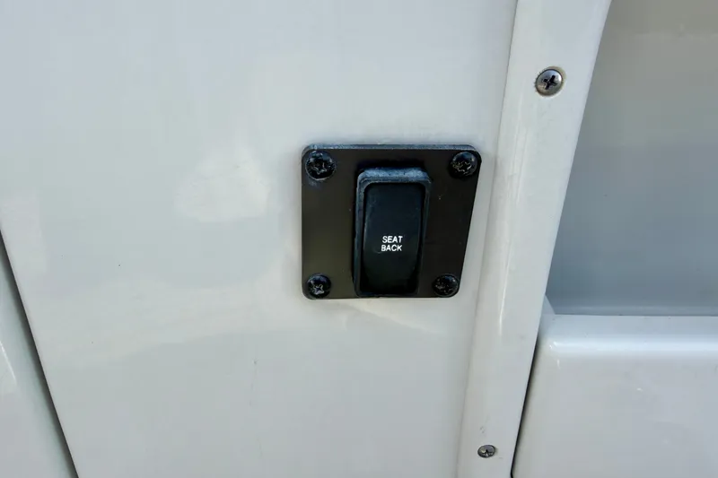 Slide: The Image of 2024 Crownline Eclipse E285 XS seat back adjustment button on white panel. - 29