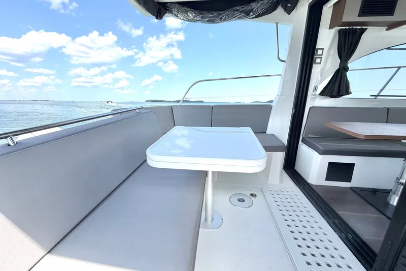 Slide: The Image of 2023 Beneteau Antares 11 OB boat interior with seating and table, overlooking serene waters. - 26