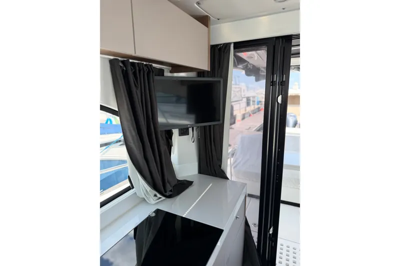Slide: The Image of Interior of 2023 Beneteau Antares 11 OB with TV, curtains, and modern cabinetry. - 28