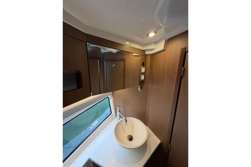 Slide: The Image of 2023 Beneteau Antares 11 OB bathroom with modern sink, wooden cabinetry, and window. - 54
