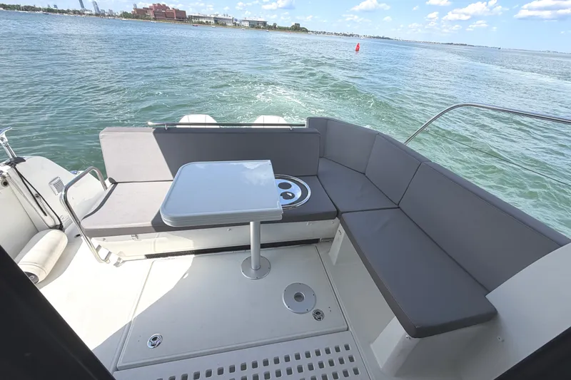 Slide: The Image of 2023 Beneteau Antares 11 OB boat deck with seating and table, overlooking calm waters. - 31