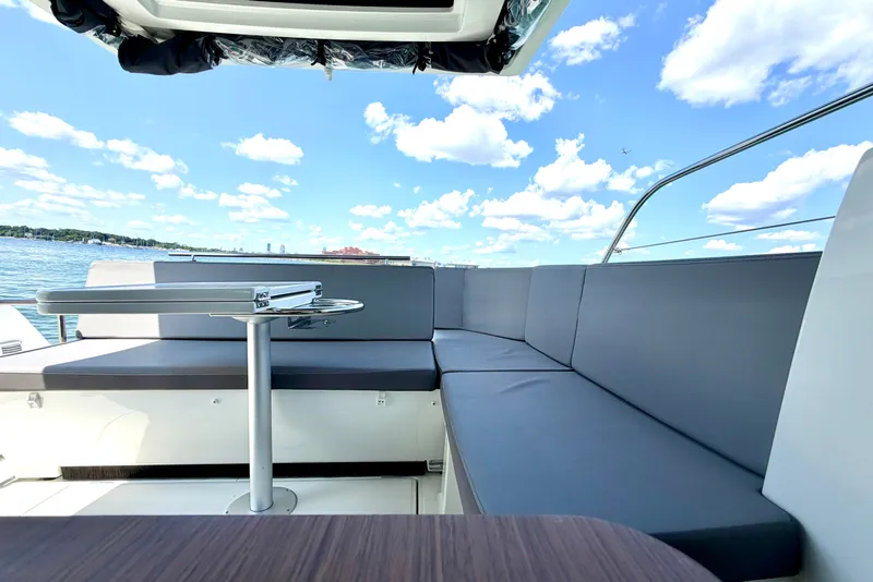 Slide: The Image of 2023 Beneteau Antares 11 OB boat interior with sleek seating and table, under a bright sky. - 27