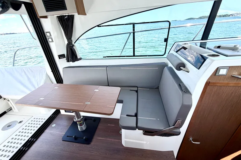 Slide: The Image of Interior of 2023 Beneteau Antares 11 OB with sleek seating and wooden table by the window. - 35