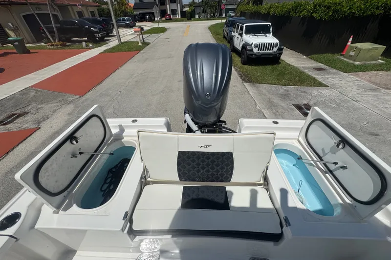 Slide: The Image of 2022 Tidewater 2410 Bay Max boat with open storage compartments and outboard motor. - 11