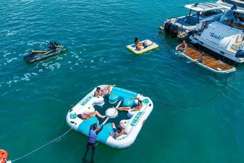 Slide: The Image of People relaxing on inflatables near a 2000 Sunseeker Manhattan 74 yacht in clear blue water. - 45