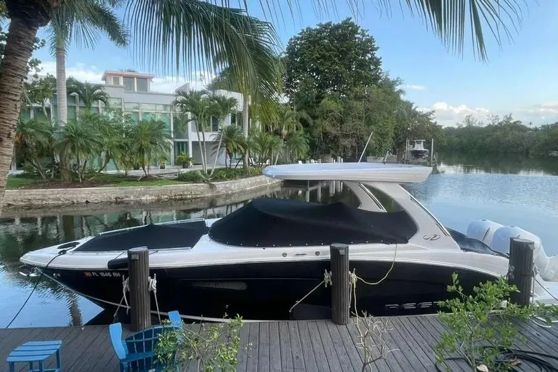 Slide: The Image of 2017 Regal 33 OBX boat docked by a scenic waterfront with lush greenery. - 4