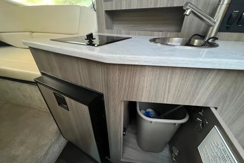Slide: The Image of 2020 Regal 26 XO boat interior with kitchenette, featuring a sink, stove, and storage. - 39