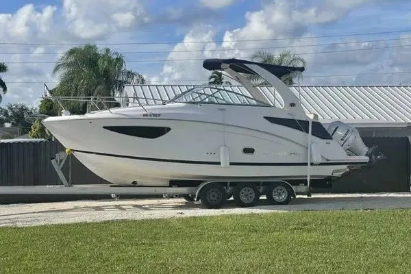 The Image of 2020 Regal 26 XO boat on trailer, parked outdoors under a cloudy sky. - 1