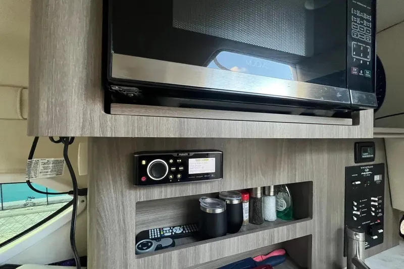 Slide: The Image of Interior of a 2020 Regal 26 XO boat featuring a microwave and control panel. - 38