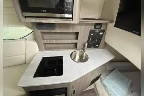 Slide: The Image of 2020 Regal 26 XO boat interior with kitchenette, featuring microwave, sink, and stovetop. - 37