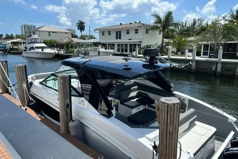 Slide: The Image of 2023 Cruisers Yachts 38 GLS OB docked by waterfront homes under a sunny sky. - 2