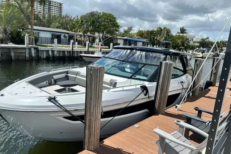 Slide: The Image of 2023 Cruisers Yachts 38 GLS OB docked by waterfront homes under cloudy skies. - 1