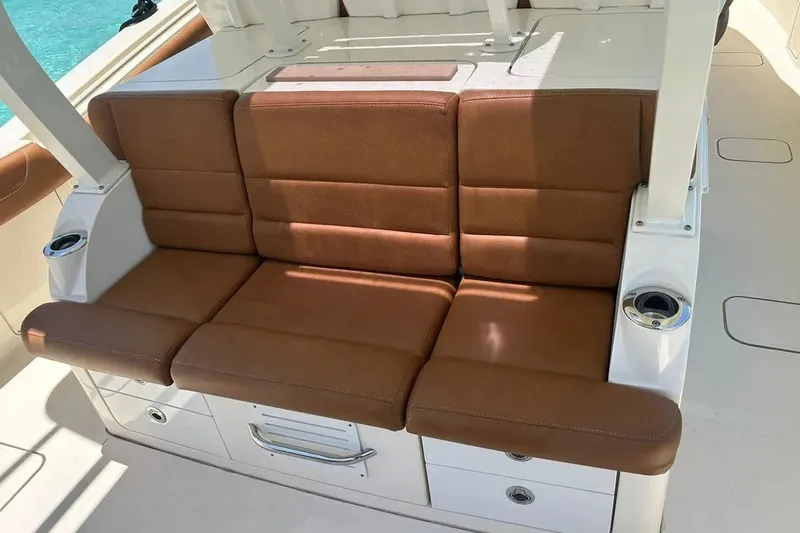 Slide: The Image of Luxurious brown seating on 2019 Scout 420 LXF boat, featuring cup holders and storage. - 31