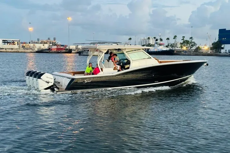 The Image of 2019 Scout 420 LXF boat cruising in a harbor with passengers onboard. - 1