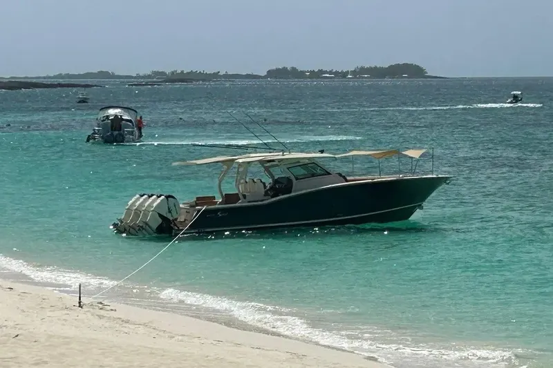 Slide: The Image of 2019 Scout 420 LXF boat anchored on turquoise waters near a sandy beach. - 10