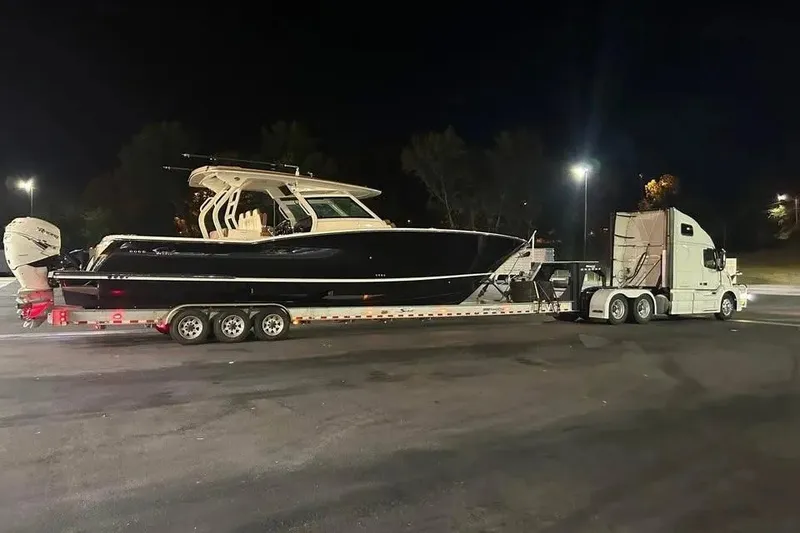 Slide: The Image of 2019 Scout 420 LXF boat on trailer, transported by a truck at night. - 11
