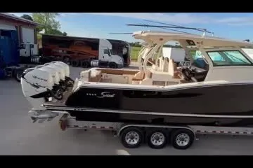 Slide: The Image of 2019 Scout 420 LXF boat on trailer, parked outdoors. - 2