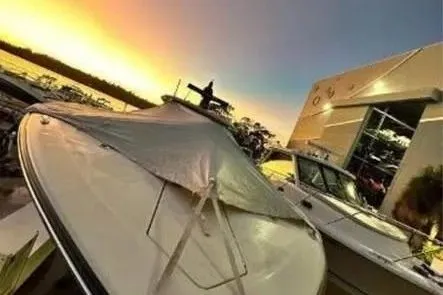 Slide: The Image of 2019 Scout 420 LXF boat docked at sunset near a modern building. - 25