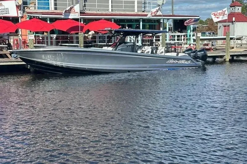 Slide: The Image of 2023 Nor-Tech 390 Center Console boat docked by waterfront restaurant with red umbrellas. - 20