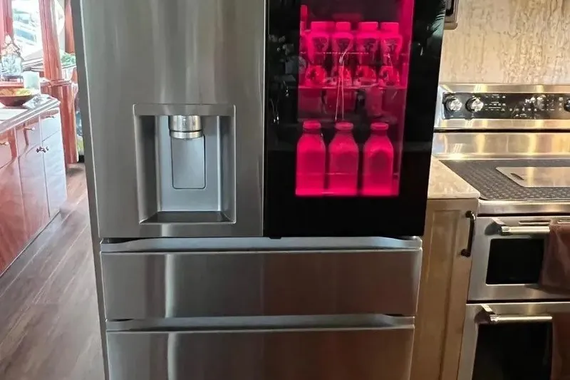 Slide: The Image of Modern kitchen with stainless steel refrigerator, red-lit beverage display, and sleek appliances on a 2004 Lazzara SC Motor Yacht. - 24