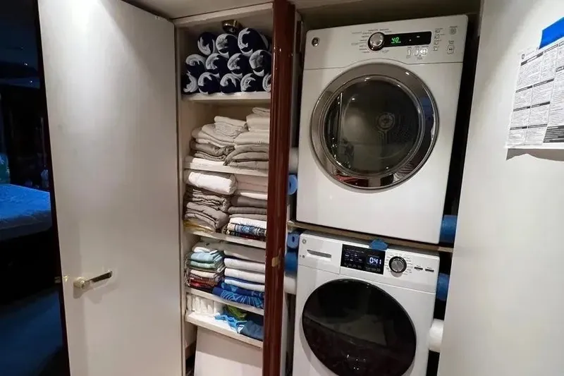 Slide: The Image of Laundry area with stacked washer and dryer, neatly organized towels on Lazzara SC Motor Yacht. - 37
