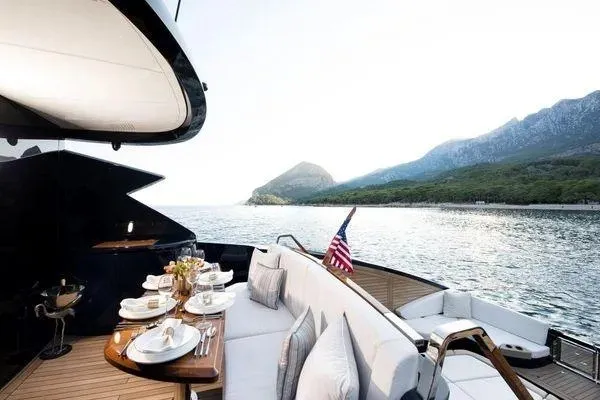 Slide: The Image of Luxurious 2023 Lazzara LSX 67 yacht with elegant dining setup, scenic coastal view. - 26