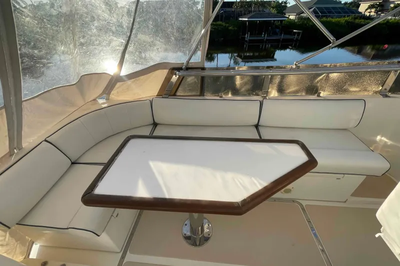 Slide: The Image of 2002 President Trawler interior with white cushioned seating and table, overlooking serene water view. - 79