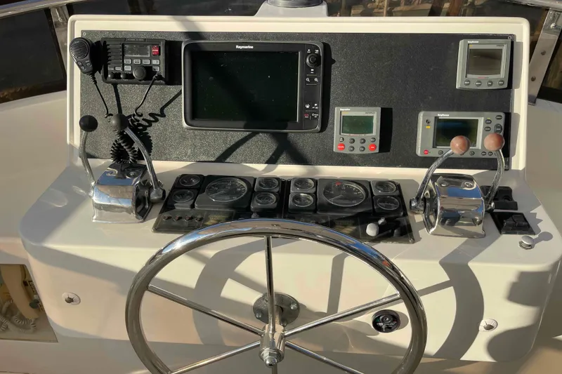 Slide: The Image of Control panel of a 2002 President Trawler with navigation instruments and steering wheel. - 74