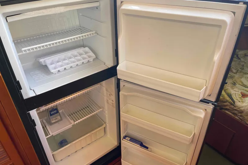 Slide: The Image of Open refrigerator in a 2002 President Trawler, showing empty shelves and ice tray. - 54