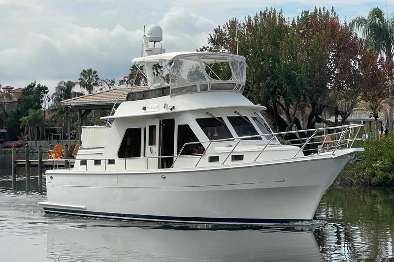 The Image of 2002 President Trawler yacht cruising on a calm waterway, surrounded by lush greenery. - 0