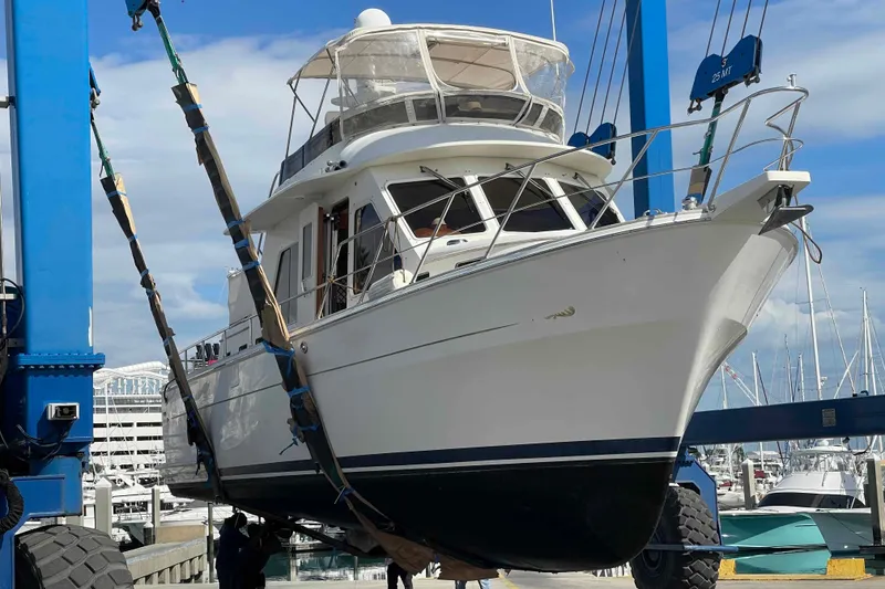 Slide: The Image of 2002 President Trawler yacht in dry dock, lifted by a blue crane at a marina. - 112